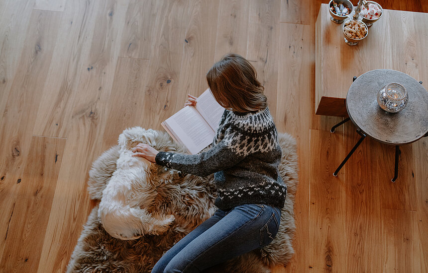 <p>Frau liest Buch und daneben liegt ein Hund</p>