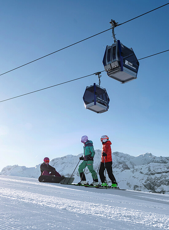<p>Zwei Skifahrer und ein Snowboarder auf der Skipiste</p>